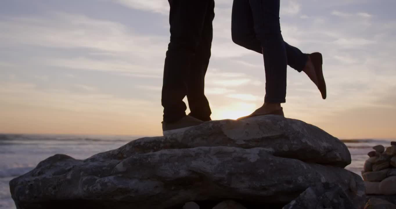 一對情侶站在海邊的一塊巖石上視頻購買