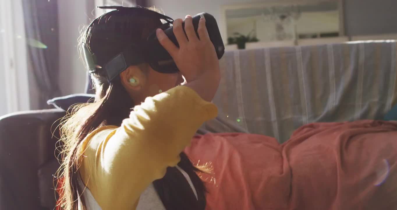 快乐的亚洲女孩在家，坐在客厅地板上使用vr头盔视频购买