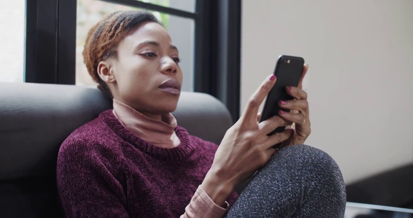 非洲妇女看着手机感到如释重负视频素材