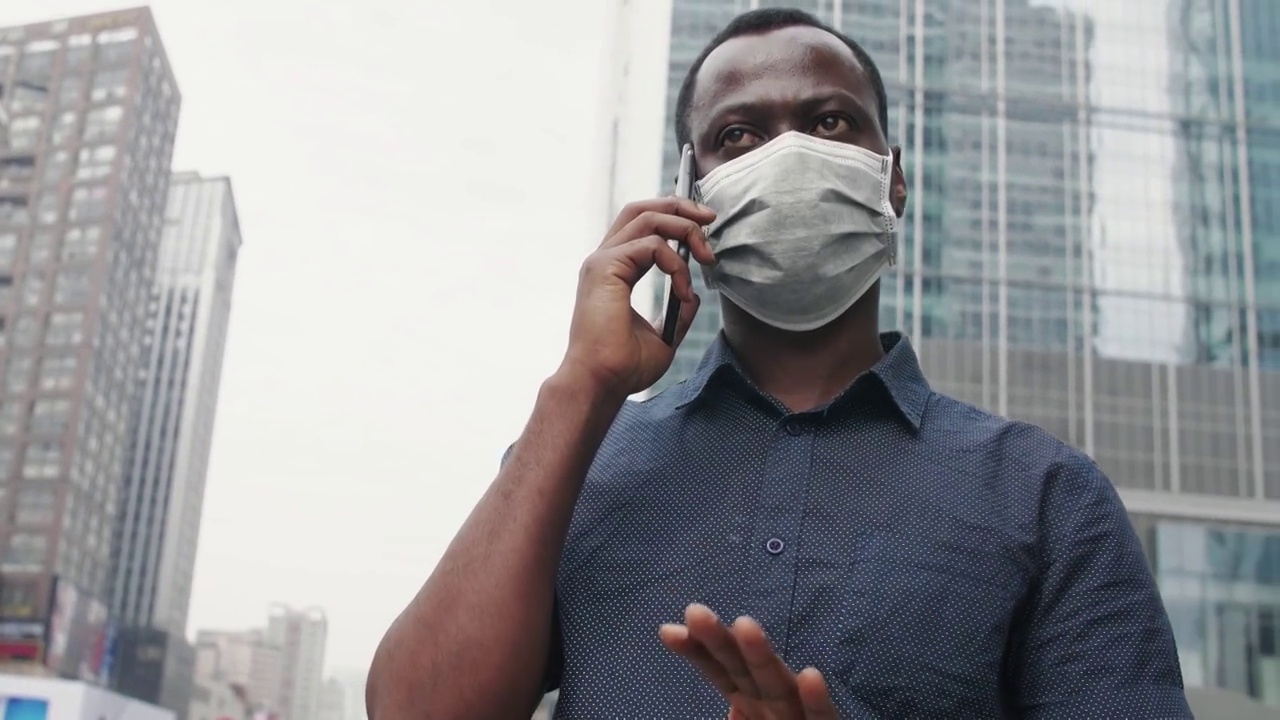 一个黑人男生戴着口罩在街上打电话视频素材