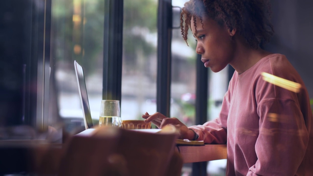 一个黑人女生坐在窗边用电脑工作视频下载