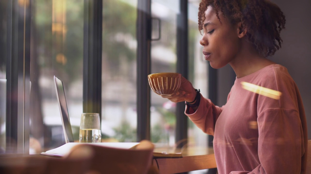 一个黑人女生坐在窗边喝咖啡视频素材