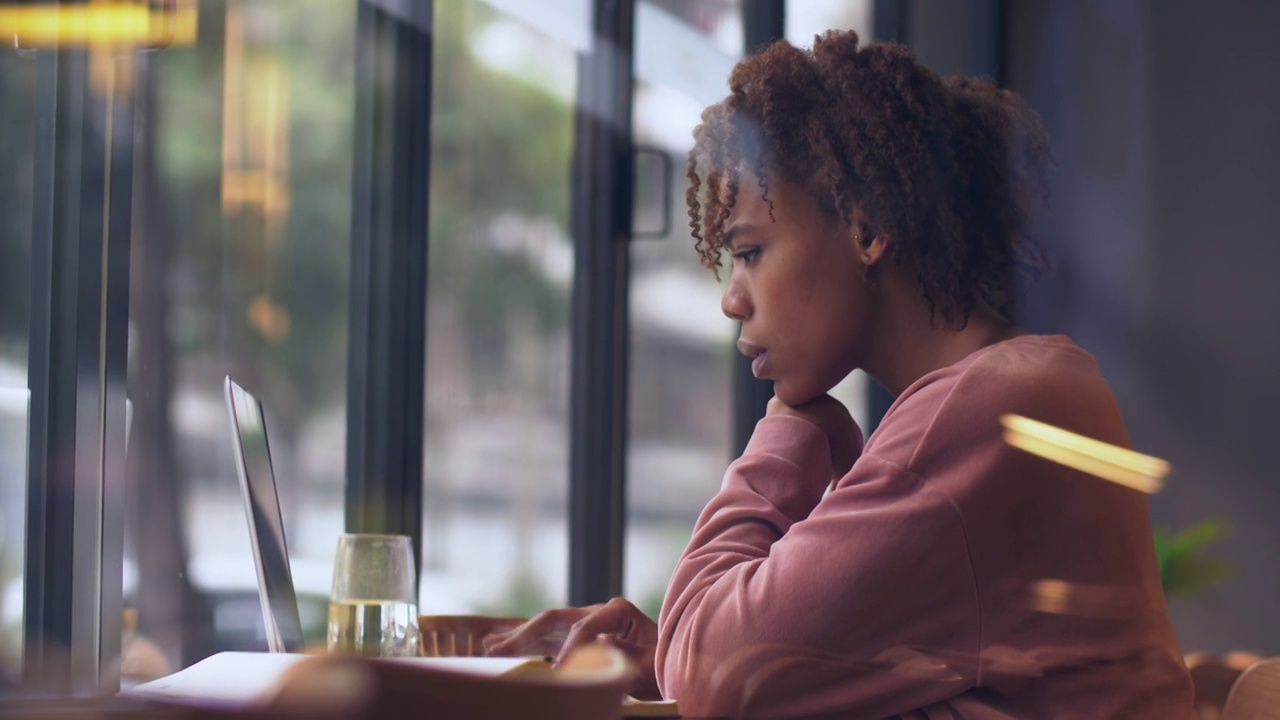 一个黑人女生坐在窗边用电脑工作视频素材