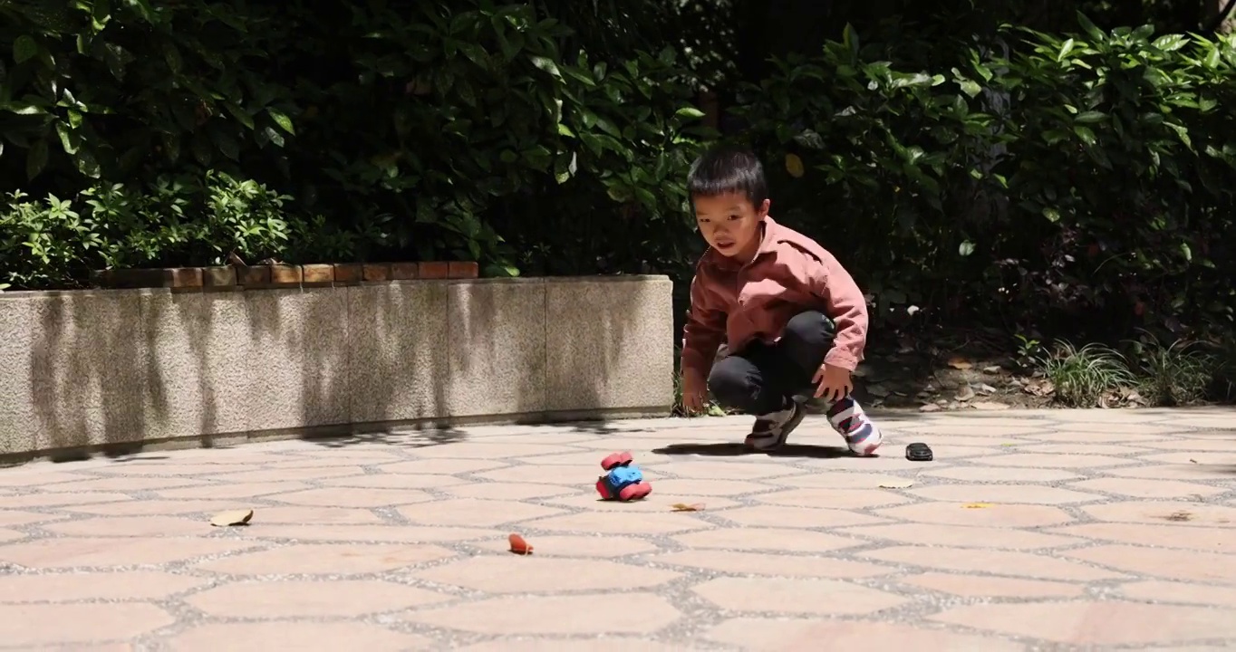 人像娱乐：小男孩在公园地上玩耍发条小汽车视频下载