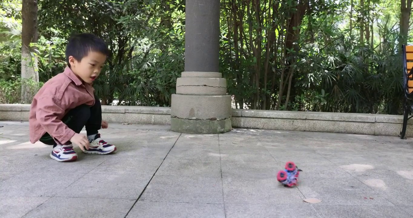 人像娱乐：小男孩在公园地上玩耍发条小汽车视频下载