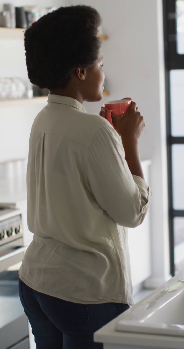 垂直视频快乐的非洲裔美国女人在家里喝咖啡视频下载