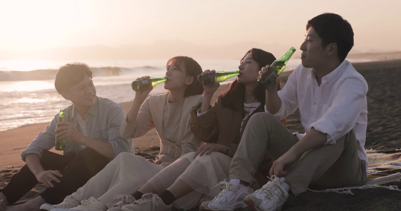 年轻的日本朋友在海滩上欣赏日落视频素材