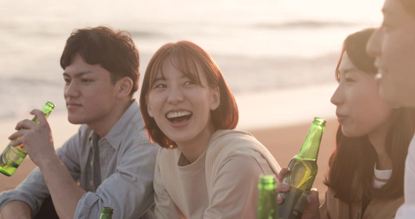 年轻的日本朋友在海滩上欣赏日落视频素材