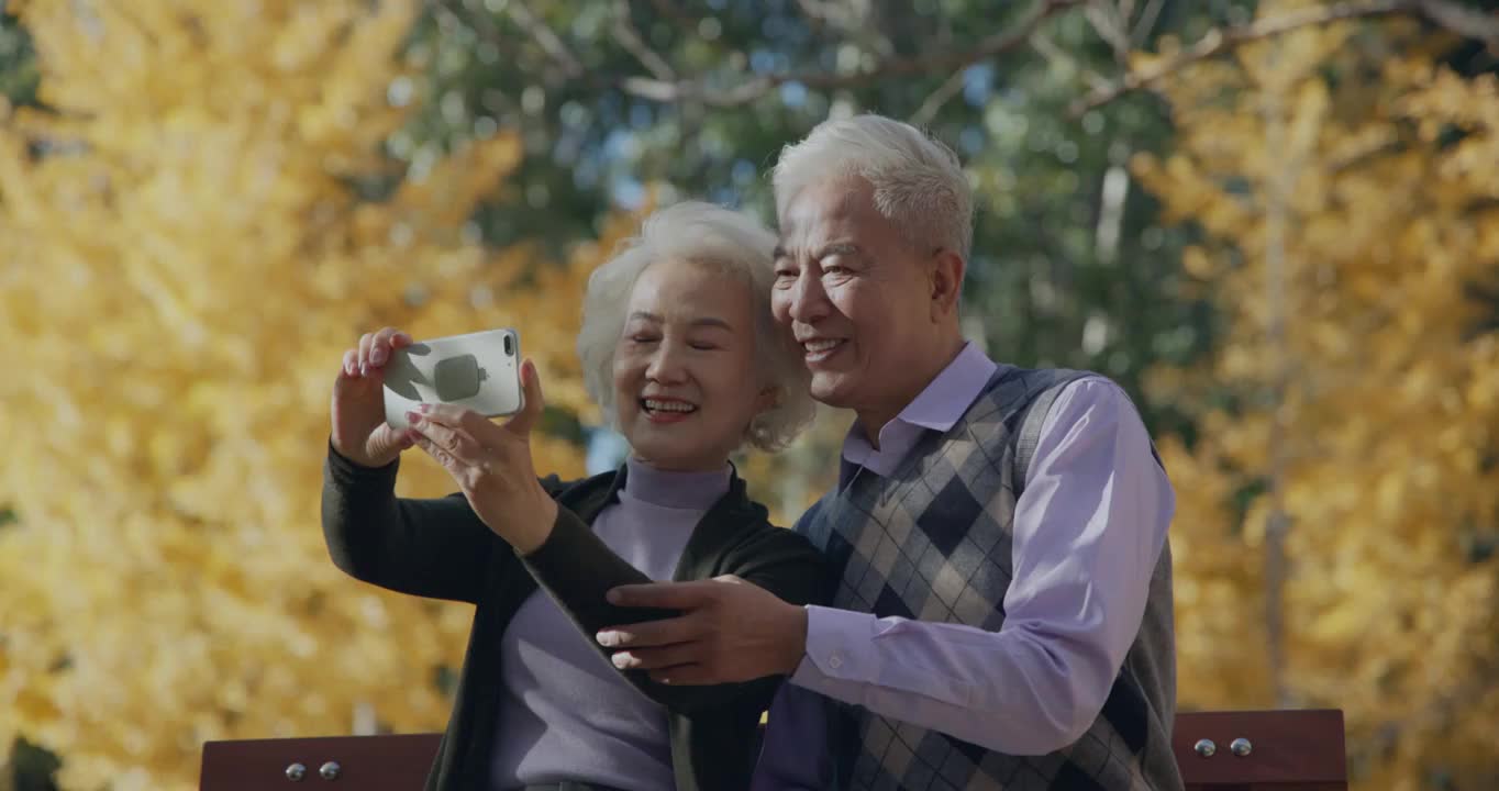 幸福的老年夫妇坐在户外用手机拍照视频下载