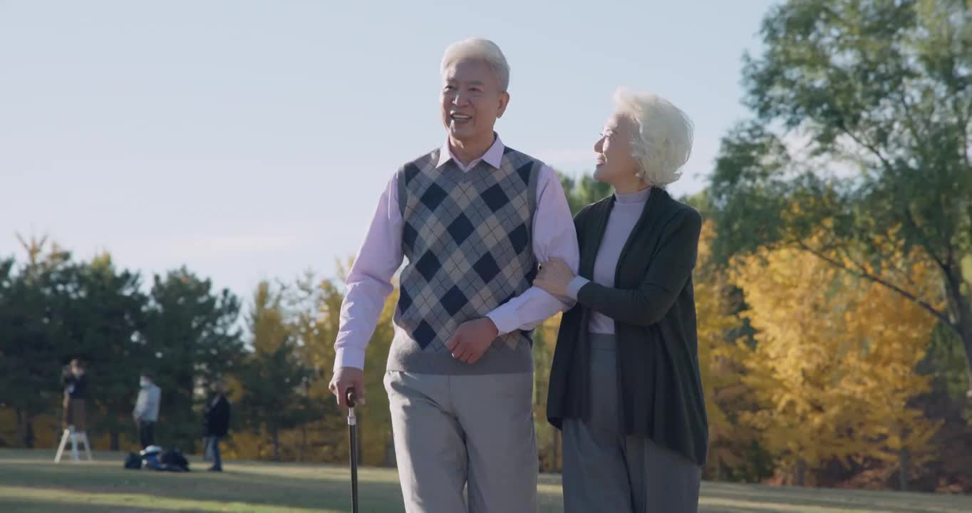 老年夫妇相互搀扶着在公园里散步视频下载