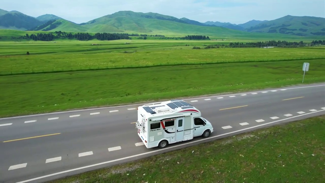 房车行驶在新疆伊犁唐布拉草原百里画廊的公路上，无人机跟拍旅行绝美画卷。视频下载