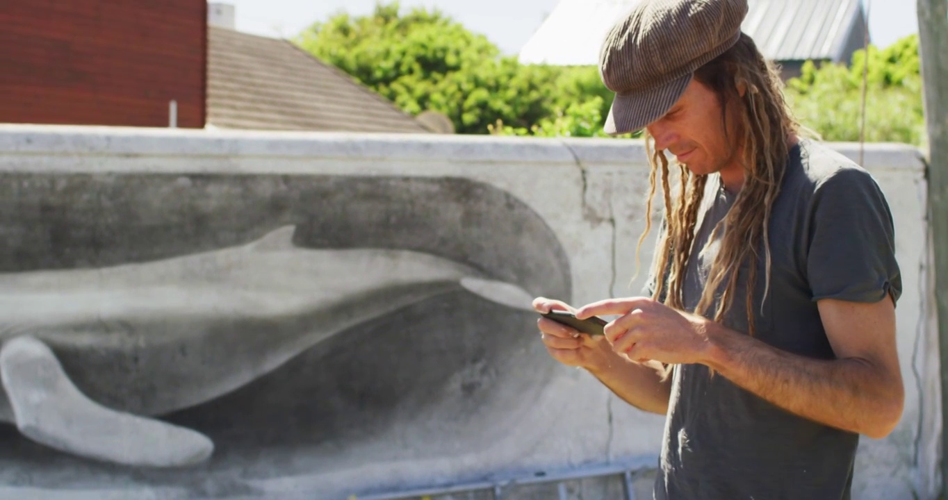 留着脏辫的白人男艺术家用智能手机拍摄鲸鱼壁画的视频视频下载