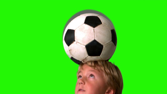 绿色屏幕上的慢镜头里，小男孩用头球顶着足球视频素材