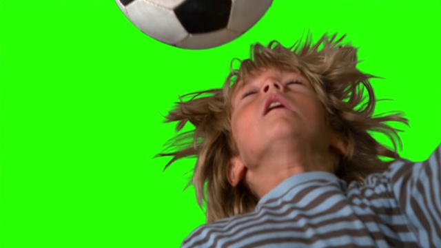 一个男孩在绿色屏幕上用慢镜头顶着足球视频素材