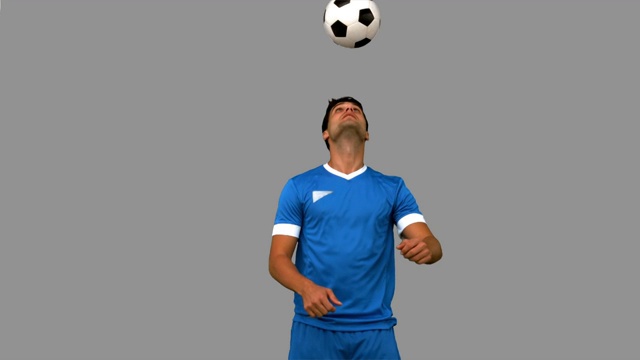 一名男子在灰色屏幕上用头部抛球，动作缓慢视频下载