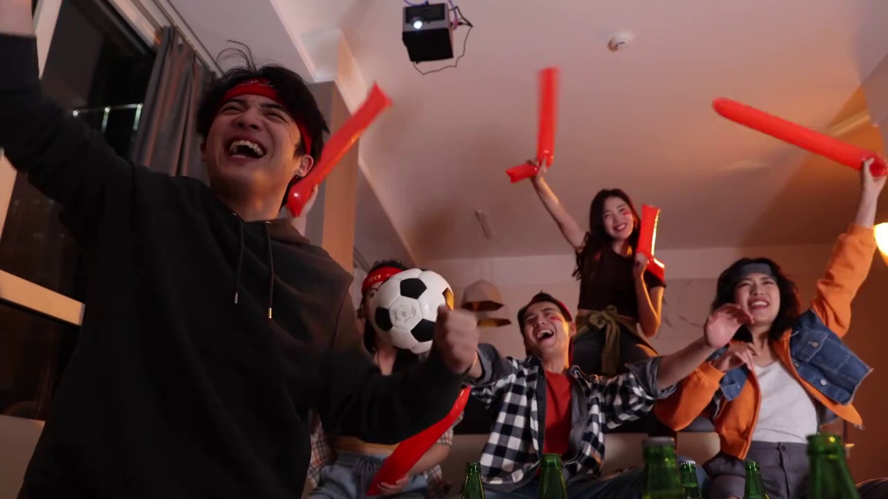 快乐的年轻人在客厅观看足球比赛:欢呼呐喊庆祝胜利视频素材