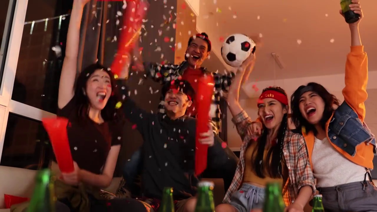 快乐的年轻人在客厅观看足球比赛:欢呼呐喊庆祝胜利视频下载
