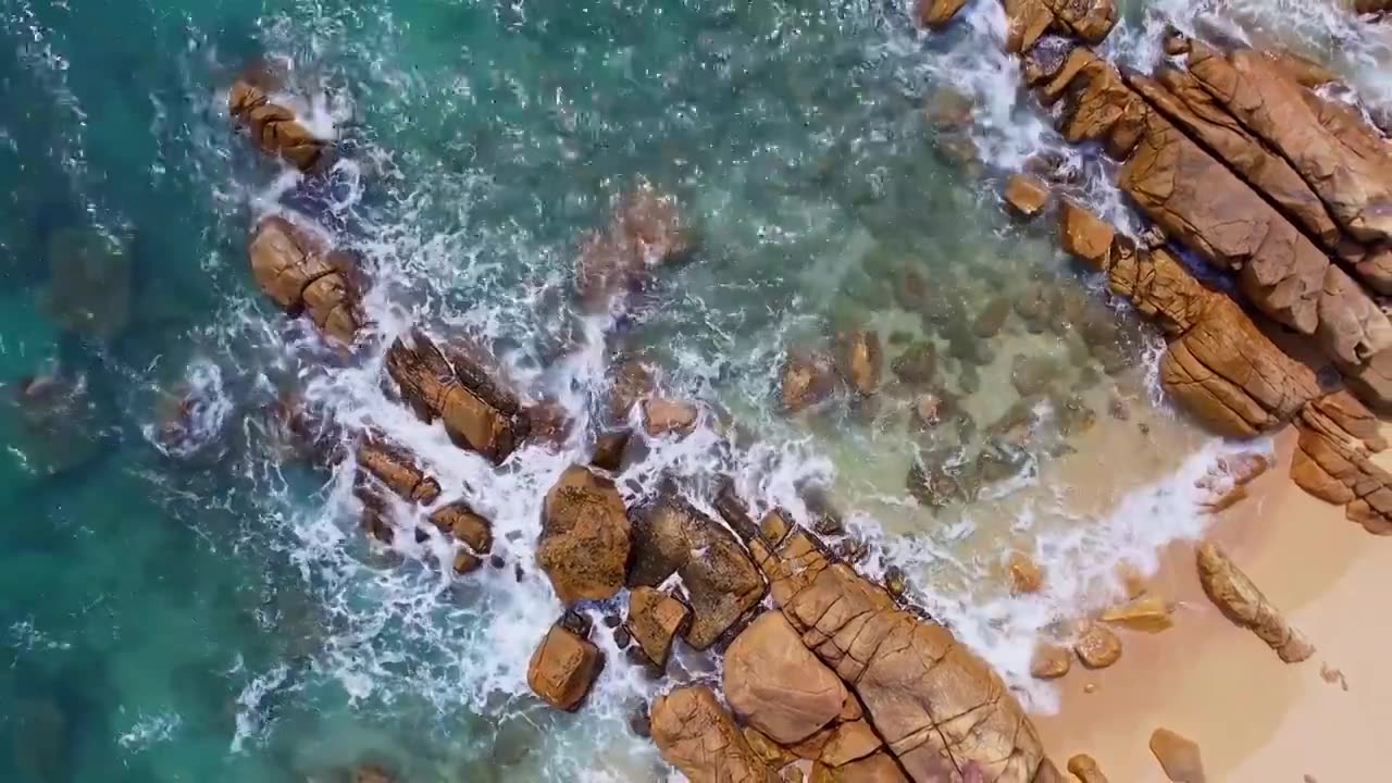 中国海南三亚三美湾大海沙滩和礁石正上方视角俯拍航拍视频素材