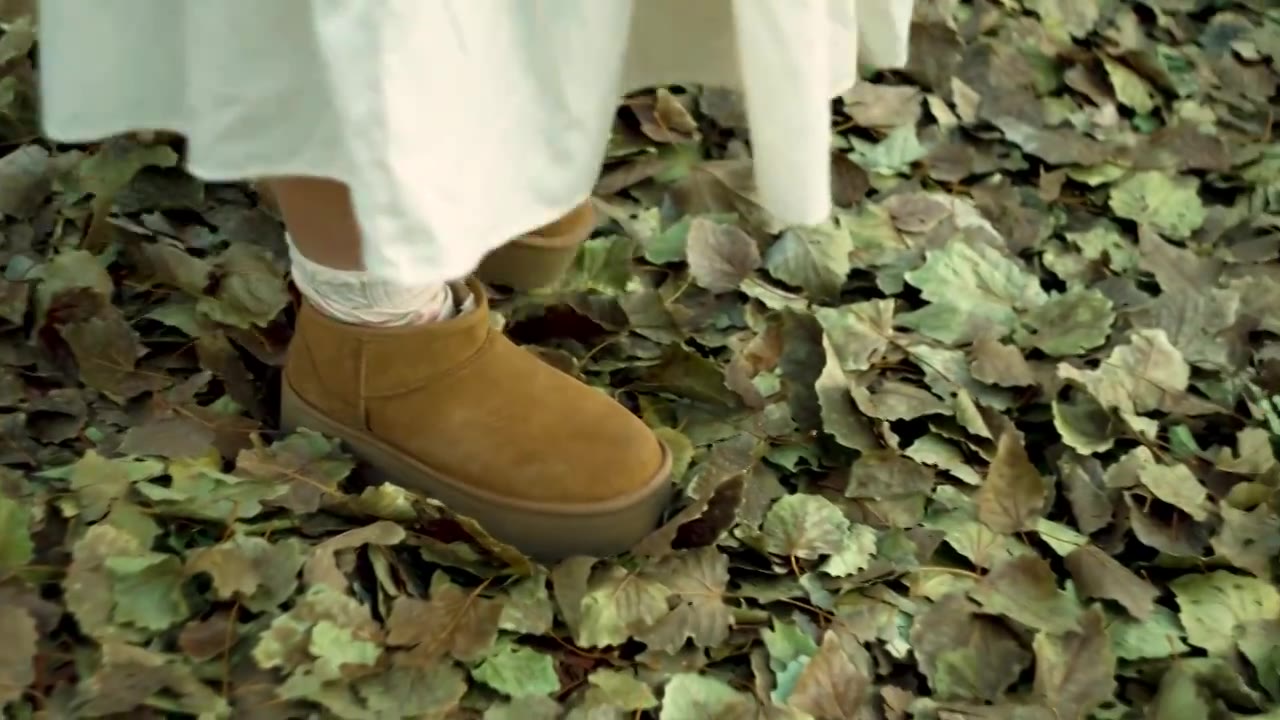 连衣裙女孩穿着皮靴踩在晚秋的落叶上视频下载