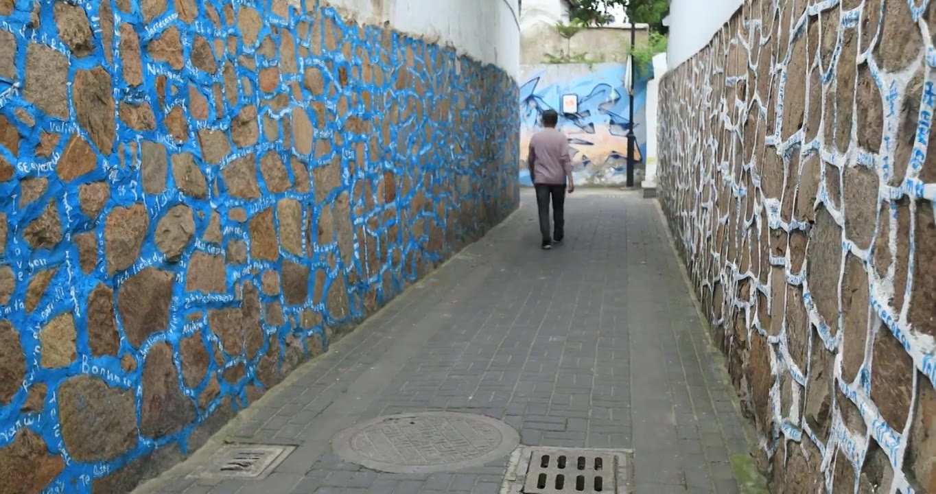 老人走在特色涂鸦墙小巷的背影视频下载