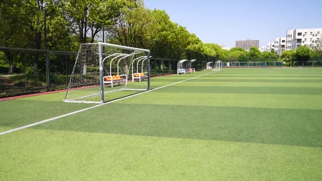 晴朗天气大学校园里露天人造草坪足球场的景观设计视频下载