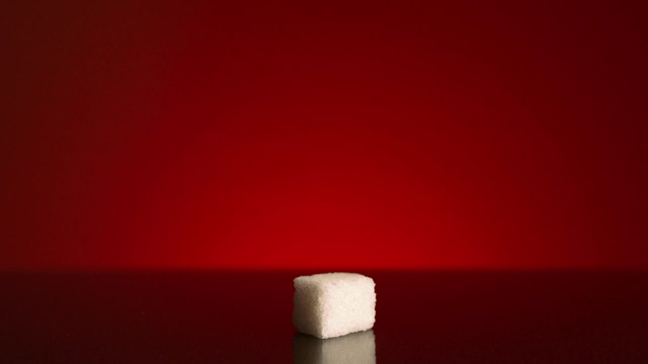 红色背景上孤立的一块方糖。资料片。一张特写视频下载