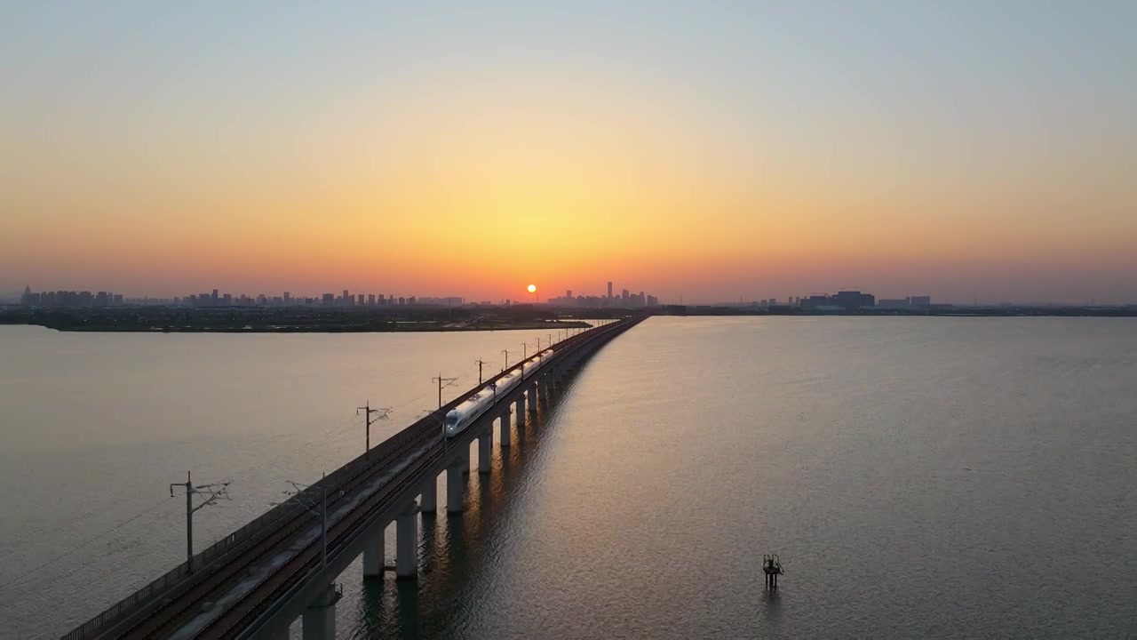 日落时分京沪高铁行驶在苏州相城工业园区阳澄湖上自然城市风景航拍视频下载