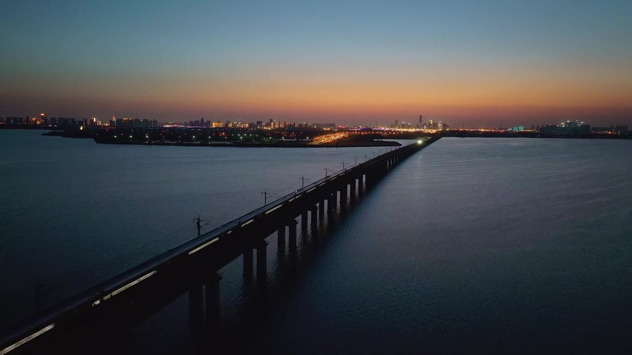 日落时分京沪高铁行驶在苏州相城工业园区阳澄湖上自然城市风景航拍视频下载