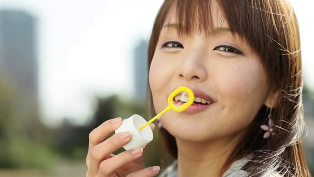 迷人的年轻日本女孩肖像吹肥皂泡视频素材