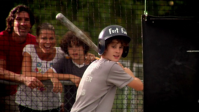 男孩在击球笼中击球，家人在外面观看/打飞球/击球线视频素材