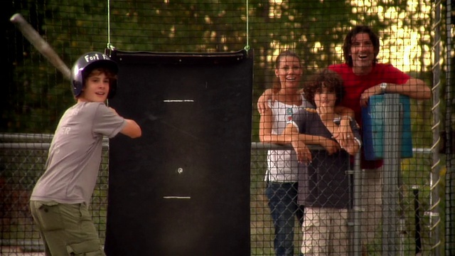 当家人在外面观看时，男孩在击球笼中击球视频下载
