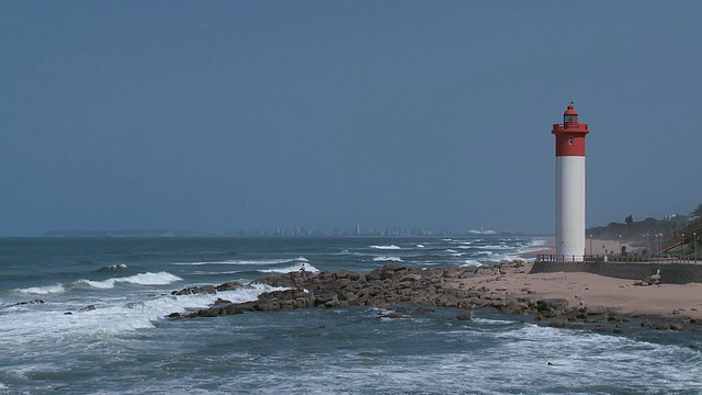 ES南非德班灯塔旁，海浪拍打着岸边的岩石视频素材