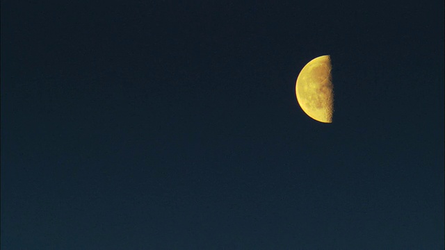 黄色的半月形月亮映衬着深蓝色的天空视频素材
