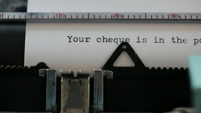 在旧打字机上打印的单词的特写:“你的支票在邮寄中”视频素材