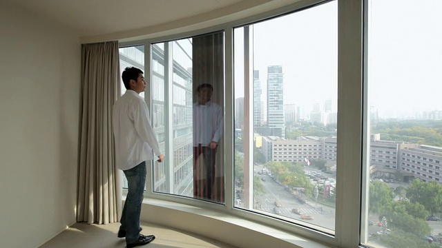 通过公寓窗户看风景的年轻人/中国视频下载