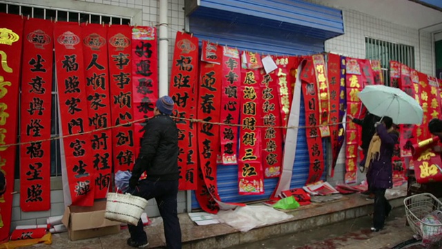 中国陕西西安，人们在雨雪天气的街道市场上购买春联视频素材