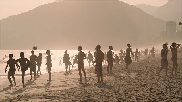 日落时分，成群的人在伊帕内玛海滩上踢足球视频素材