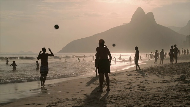 日落时分，巴西里约热内卢的伊帕内玛海滩上，年轻人在踢足球视频素材