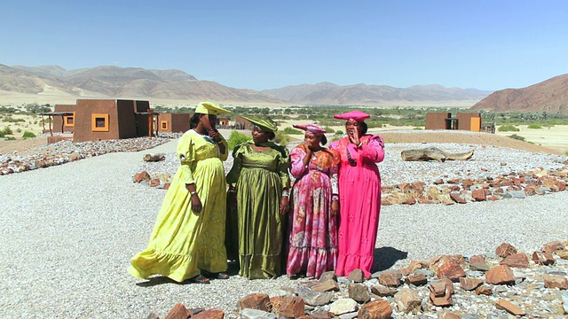 四个当地的辛巴族妇女穿着特殊的衣服唱歌和说话/纳米比亚库内的辛巴族视频下载
