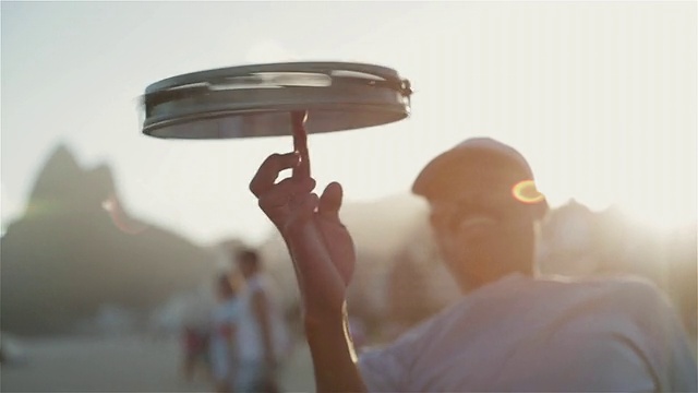 巴西里约热内卢伊帕内玛海滩上，一名男子在手指上旋转着一只小手鼓视频下载