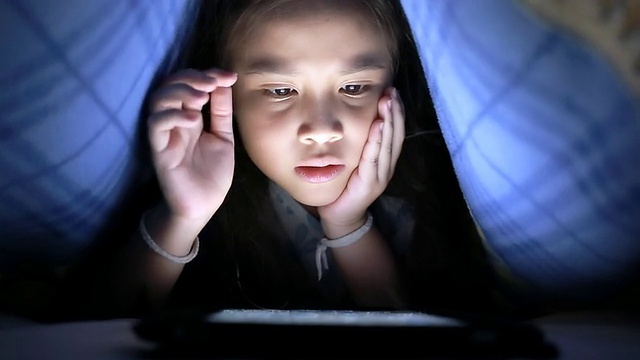 小女孩在毯子下面用平板电脑视频素材
