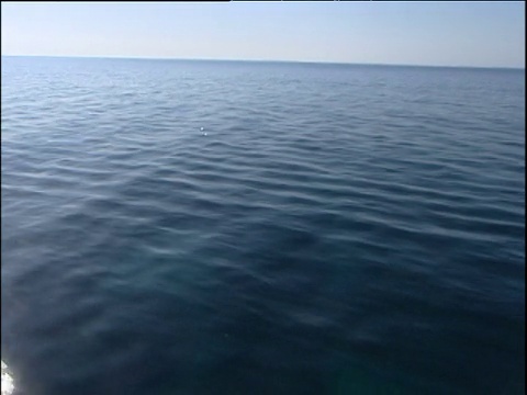 快速轨道在深蓝色的海与反射的阳光闪闪发光的表面。撒丁岛。视频下载
