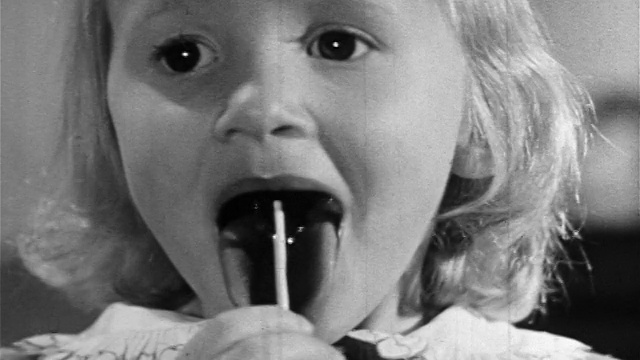 1957年B/W近距离小金发女孩舔棒棒糖/教育视频素材