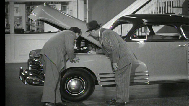 1948年汽车推销员在陈列室向人展示汽车发动机视频下载