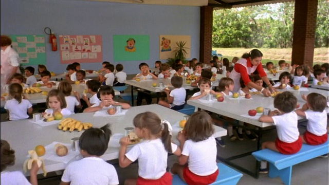 跟踪拍摄的儿童在学校/巴西的户外餐厅吃水果视频下载