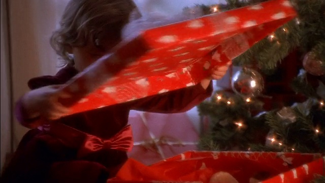 小女孩在圣诞树旁打开礼物+兴奋地抽出泰迪熊/拥抱熊视频素材