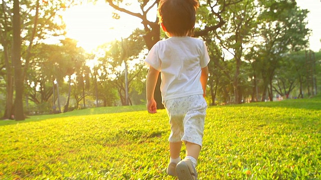日落时分，小男孩在公园里跑步。视频素材