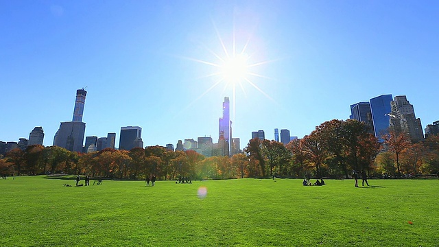 太阳从曼哈顿的摩天大楼和中央公园绵羊草地的秋日树木上照射下来。视频素材