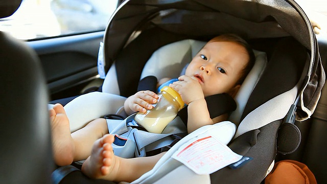 高清:一个小男孩在车里喝牛奶的照片。视频素材