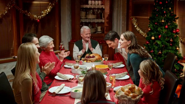 一对夫妇在圣诞餐桌上与家人分享喜讯视频素材